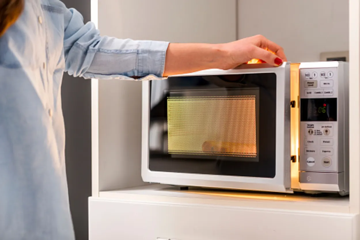 A person using microwave to prepare some food item