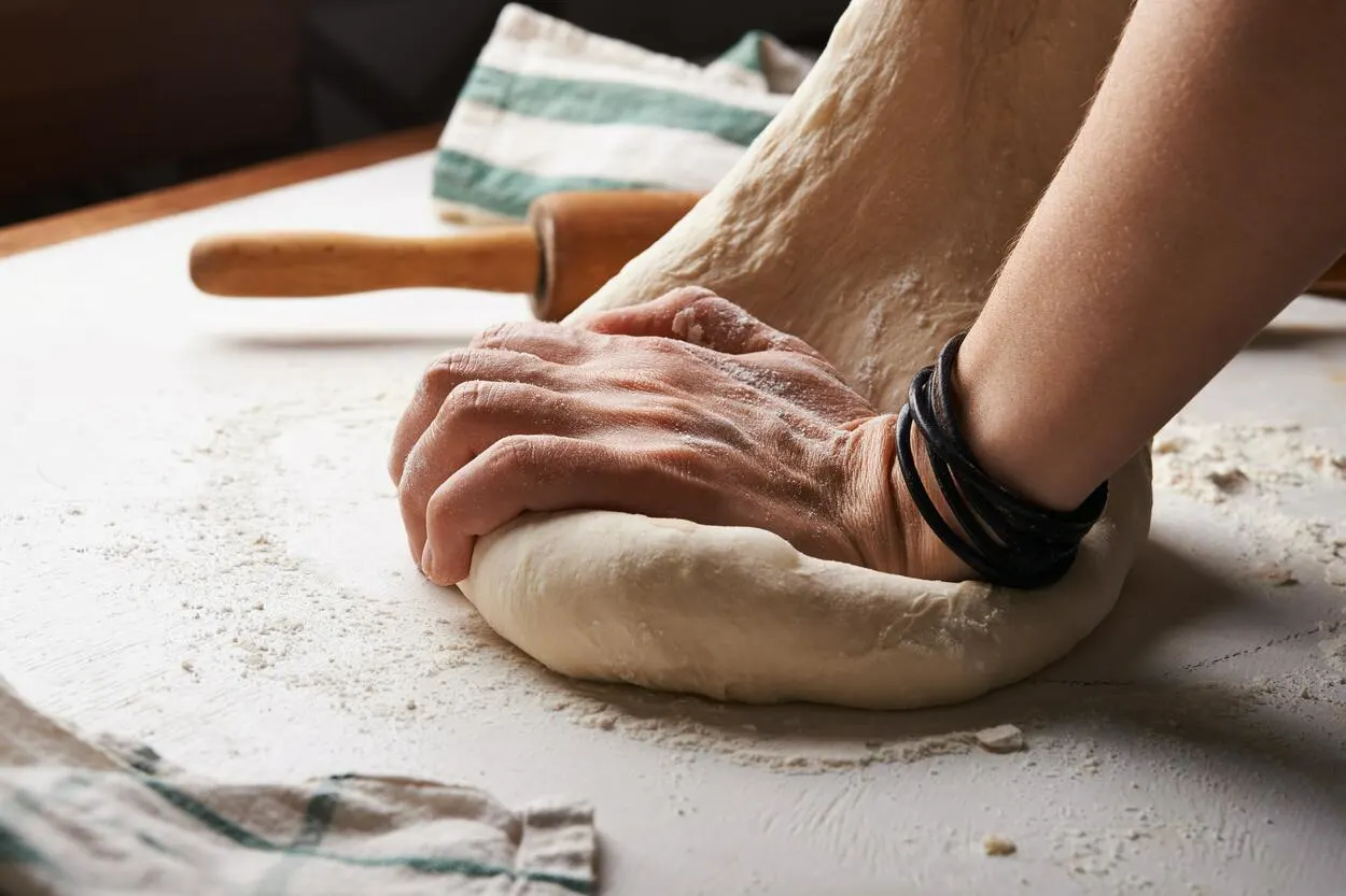 A person Kneading dough for pizza