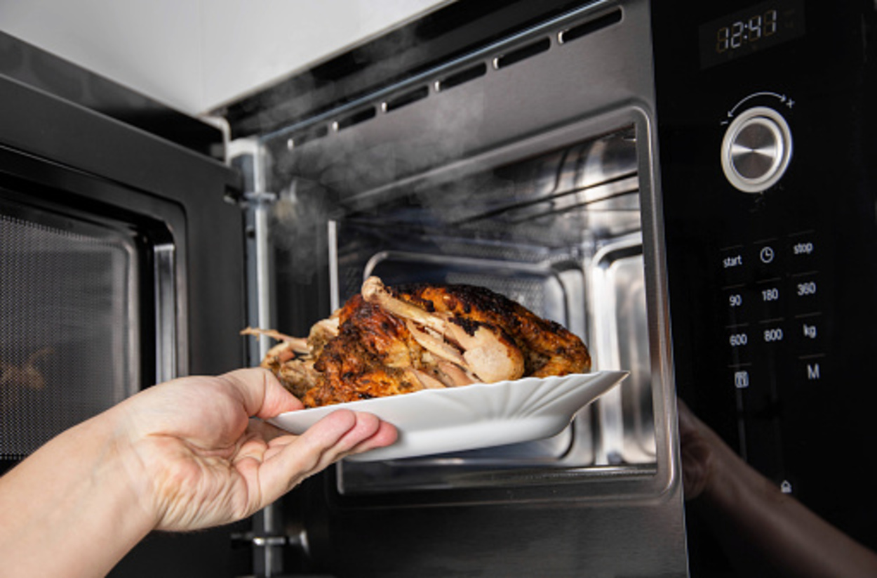 man pulling out a grilled chicken from convection microwave