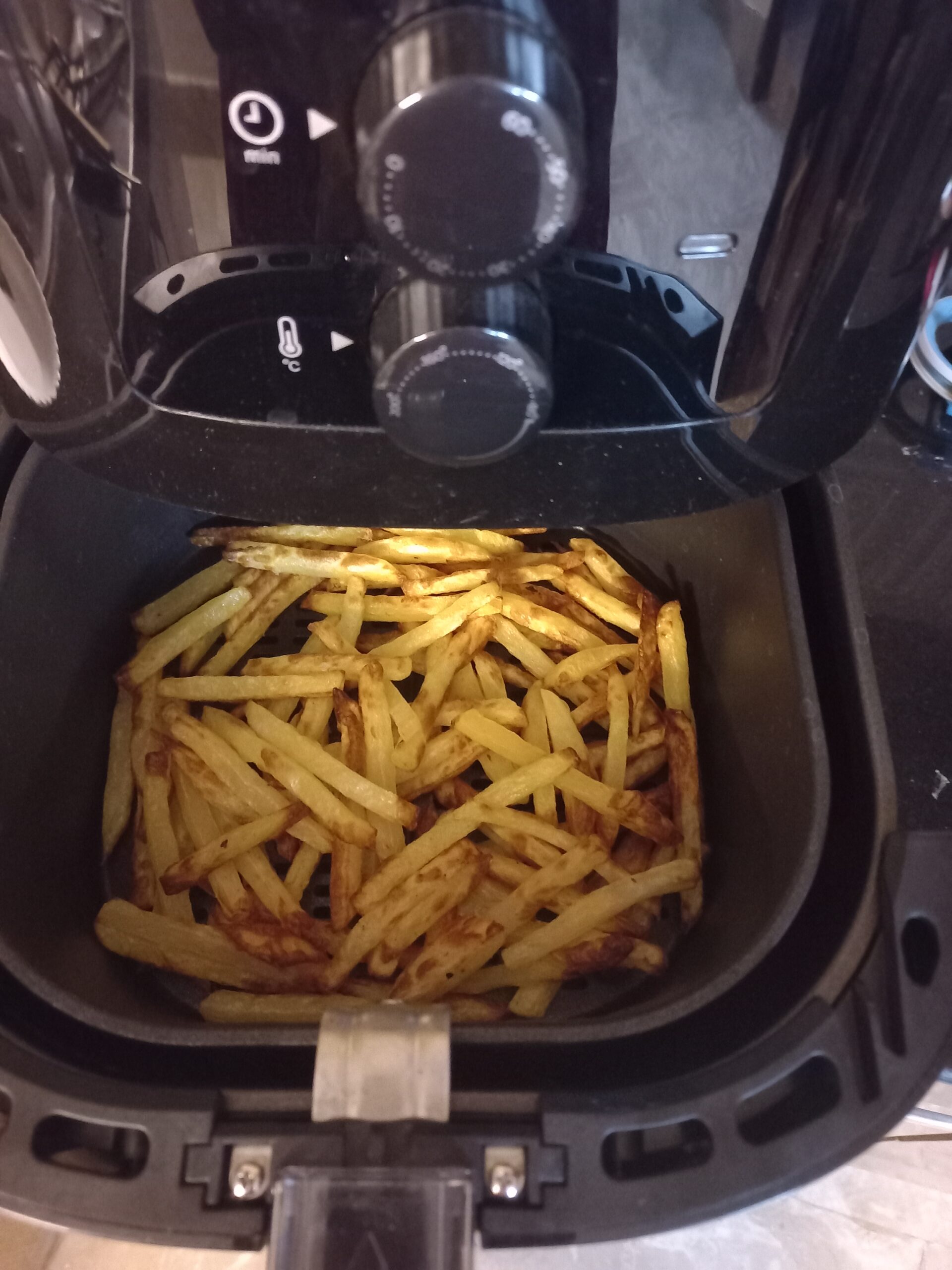 An image of french fries being cooked in an air fryer.
