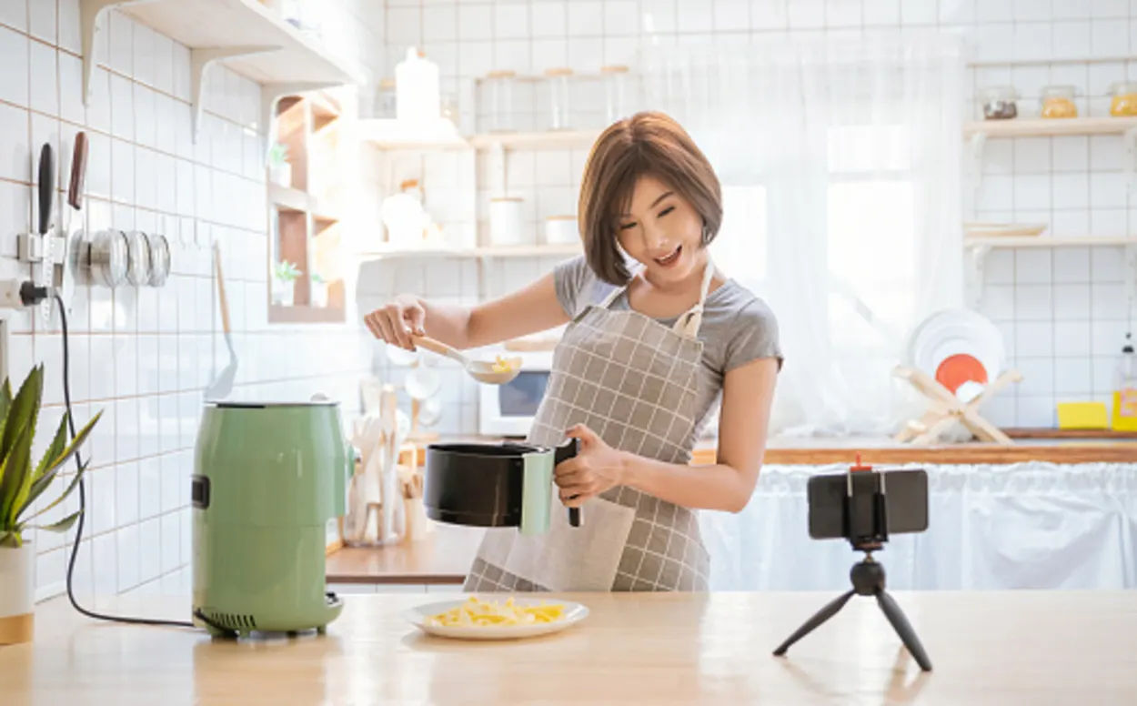 Woman recording herself while putting food in air fryer