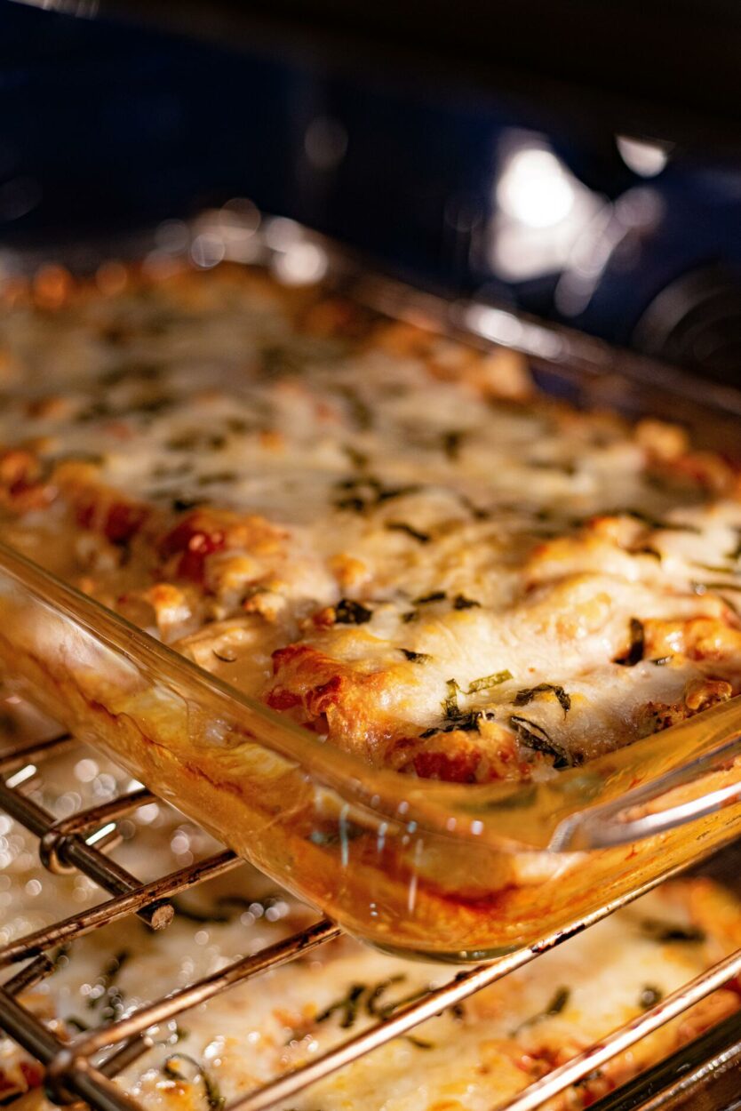 lasagna cooking in the oven safe glass container. 