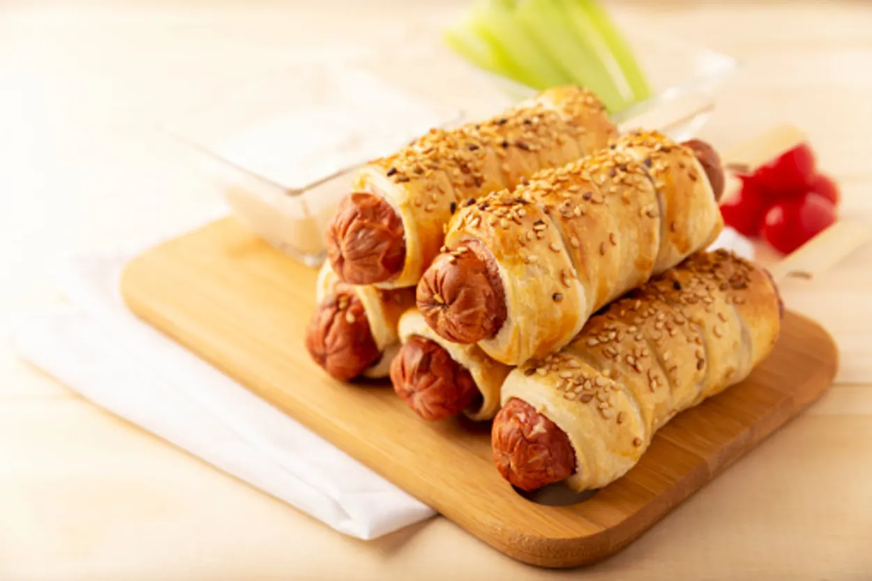Pretzel dogs on a wooden board served with cream cheese
