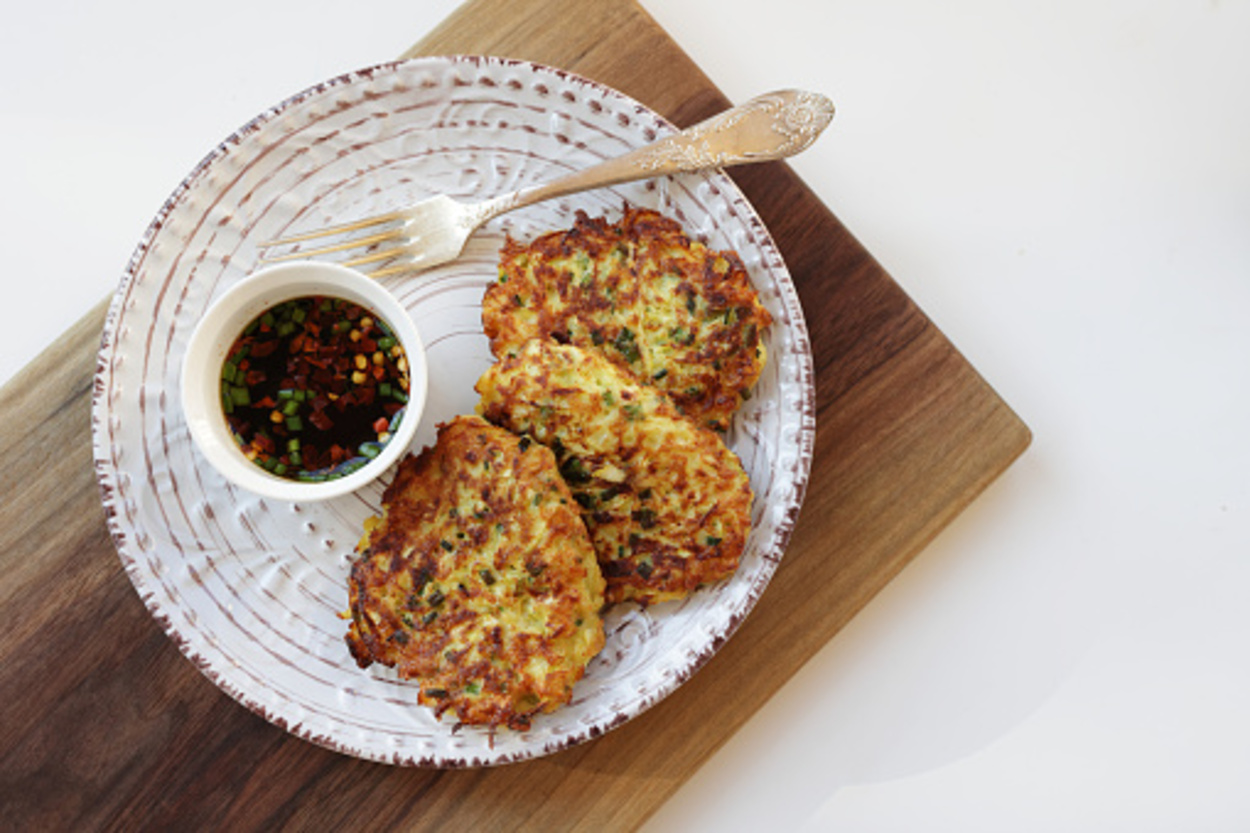 Zucchini fritters, on a white plate served with soy sauce 