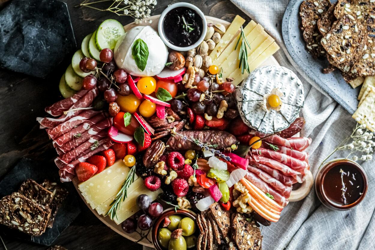 a big round charcuterie board with various colorful food 