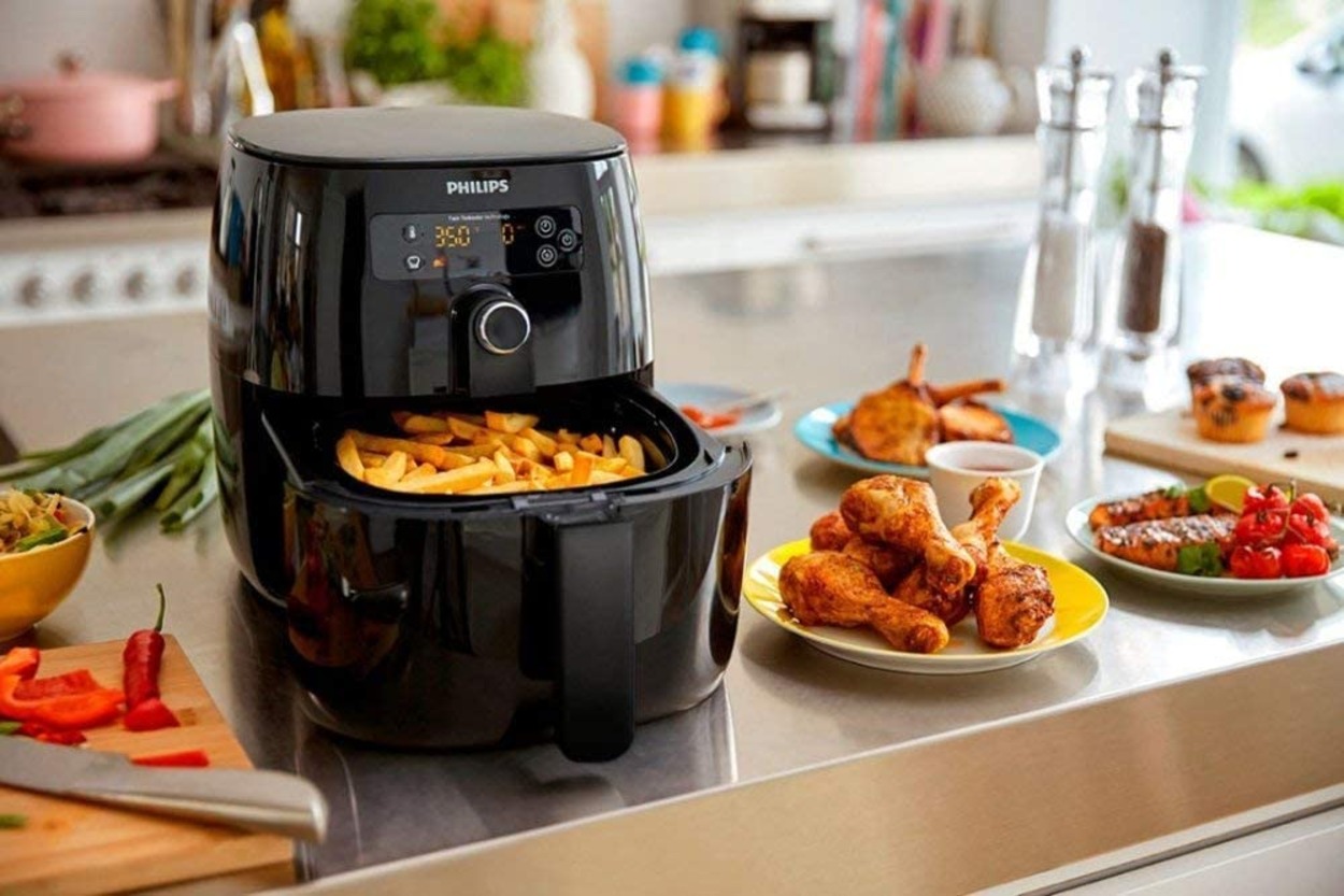 An Air fryer with French fries and some foods around