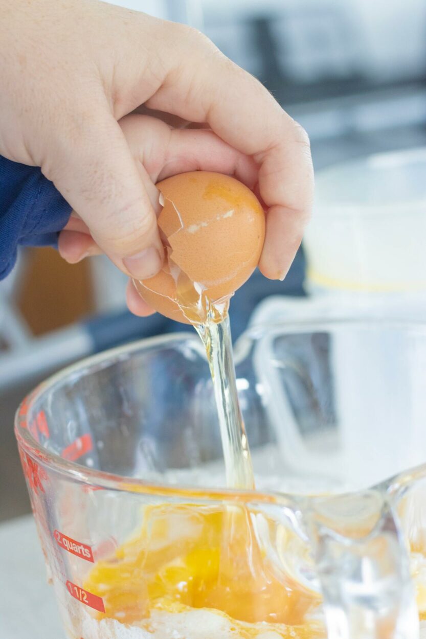 Woman adding an egg in the liquid measuring cup 