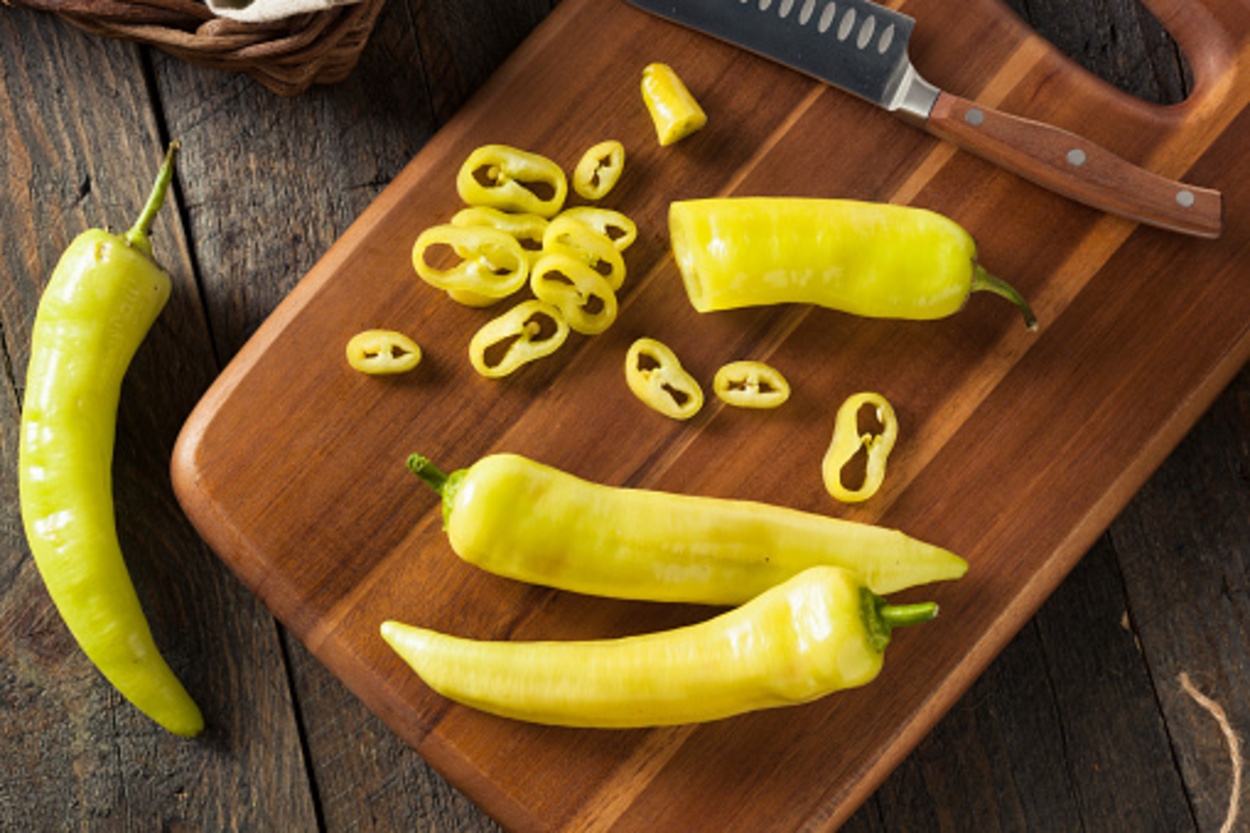 Banana peppers being chopped up on a wooden cutting board