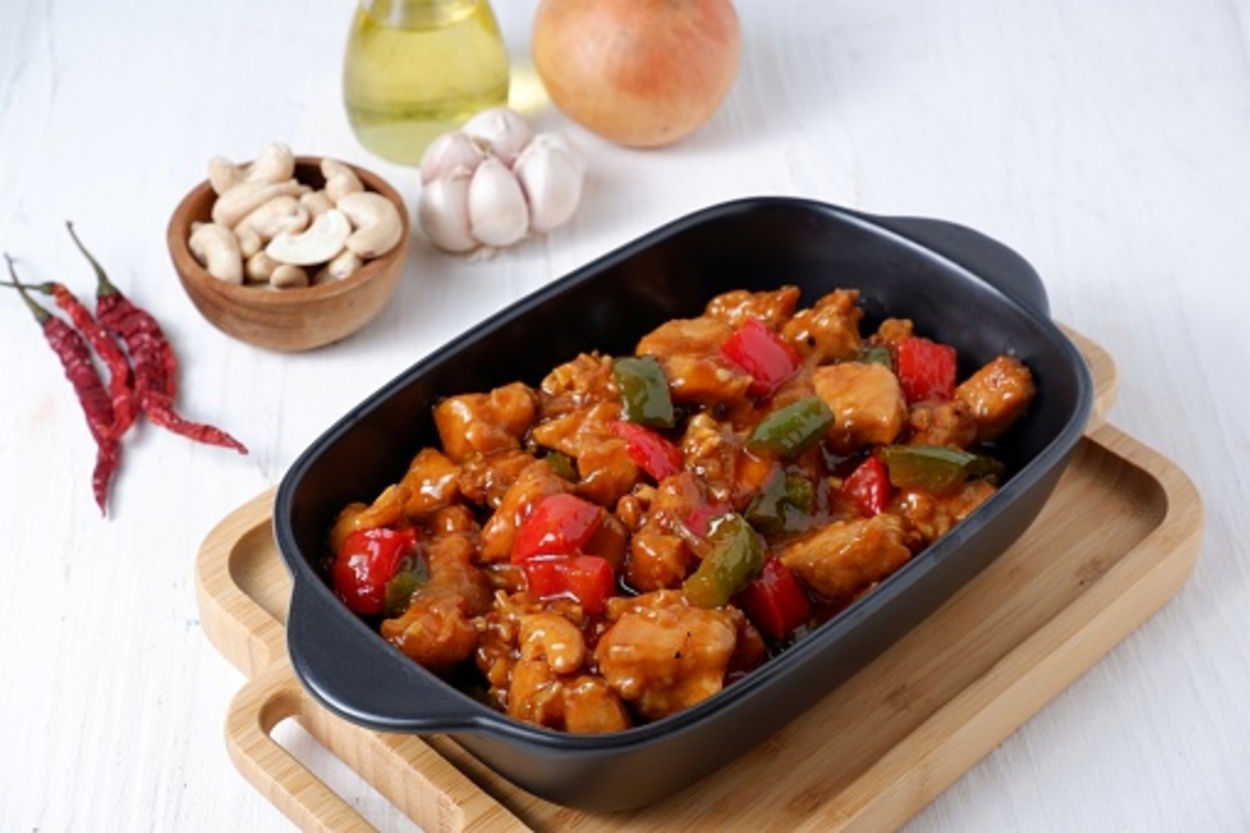 Kung pao chicken presented in a platter along with some nuts and spices