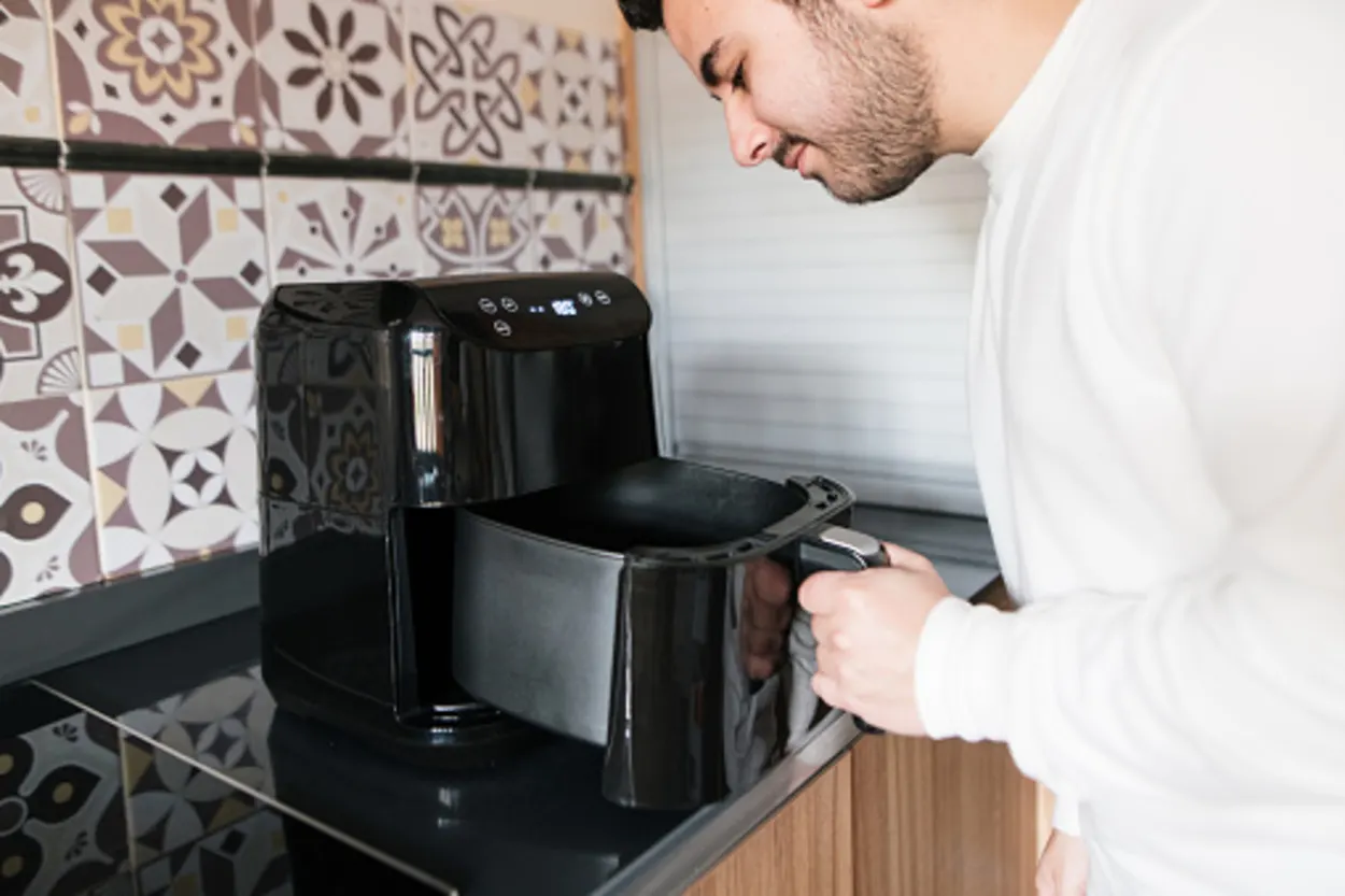 A person opening an air fryer 