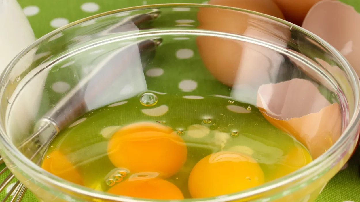 broken egg in bowl and various ingredients next to them