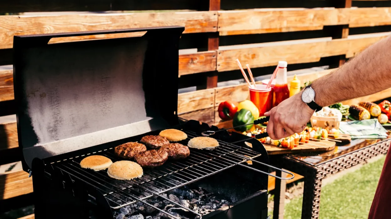 man cooking grilled meat burgers for outdoors barbecue