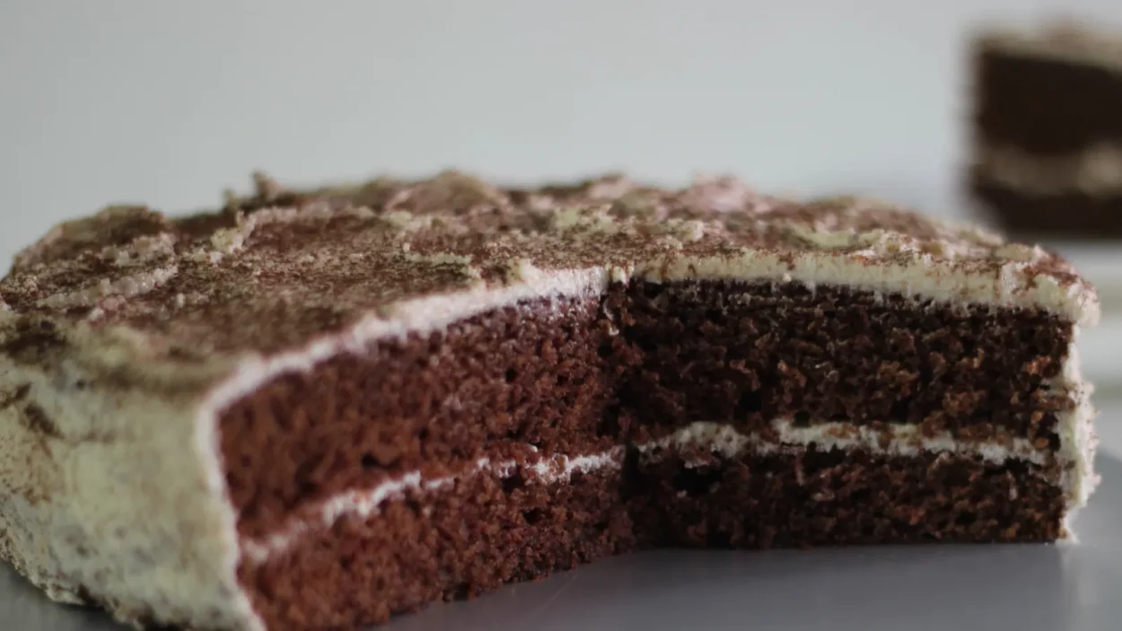 partially sliced chocolate cake with vanilla butter frosting made as