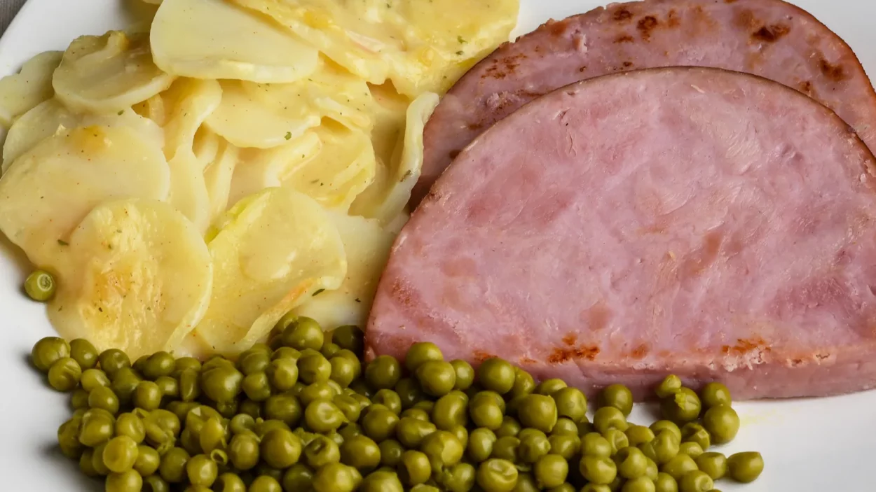 scalloped potatoes served with ham and peas