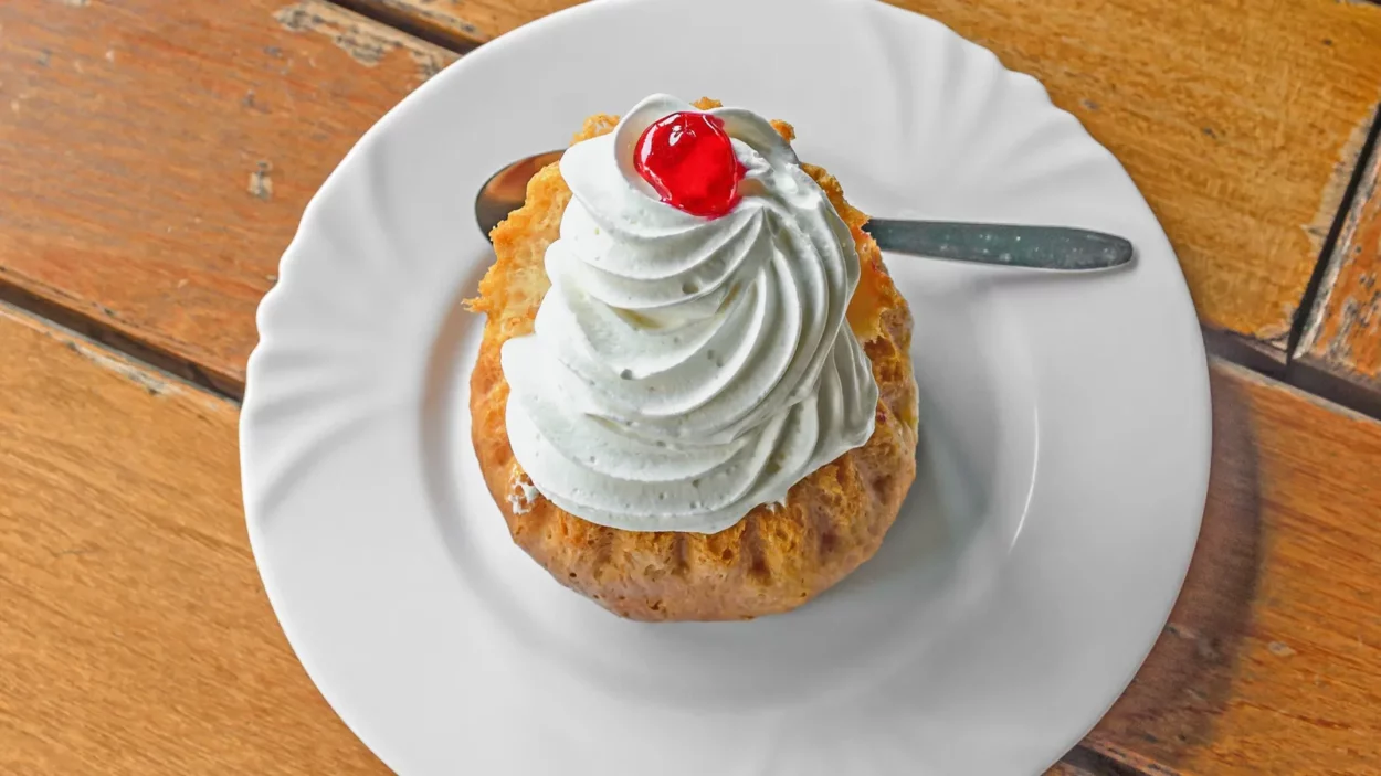 savarin cake with cream and syrup silver spoon white plate
