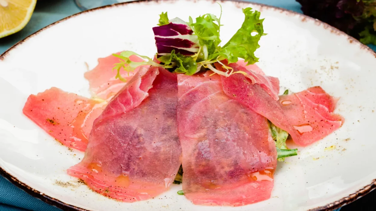 tuna carpaccio with fresh green mix salad on white plate