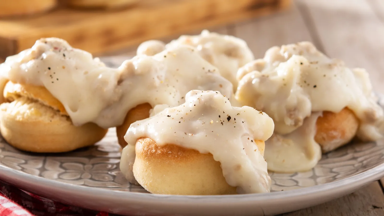 Traditional American biscuits and gravy for breakfast on wooden table.