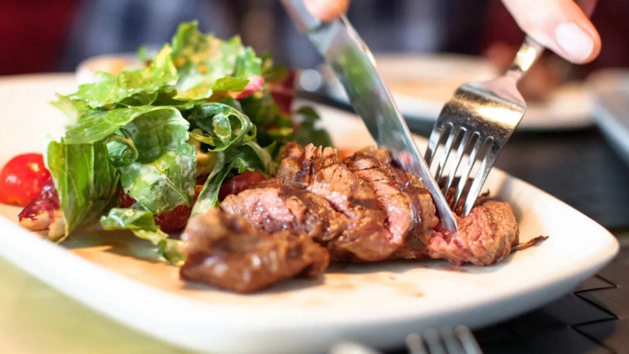 Man eating meat with salad.