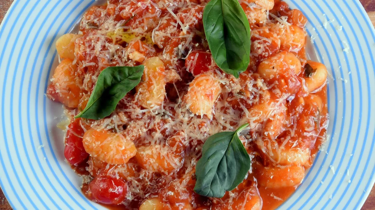 Pasta in red sauce with parmesan cheese, tomato, basil and herbs.