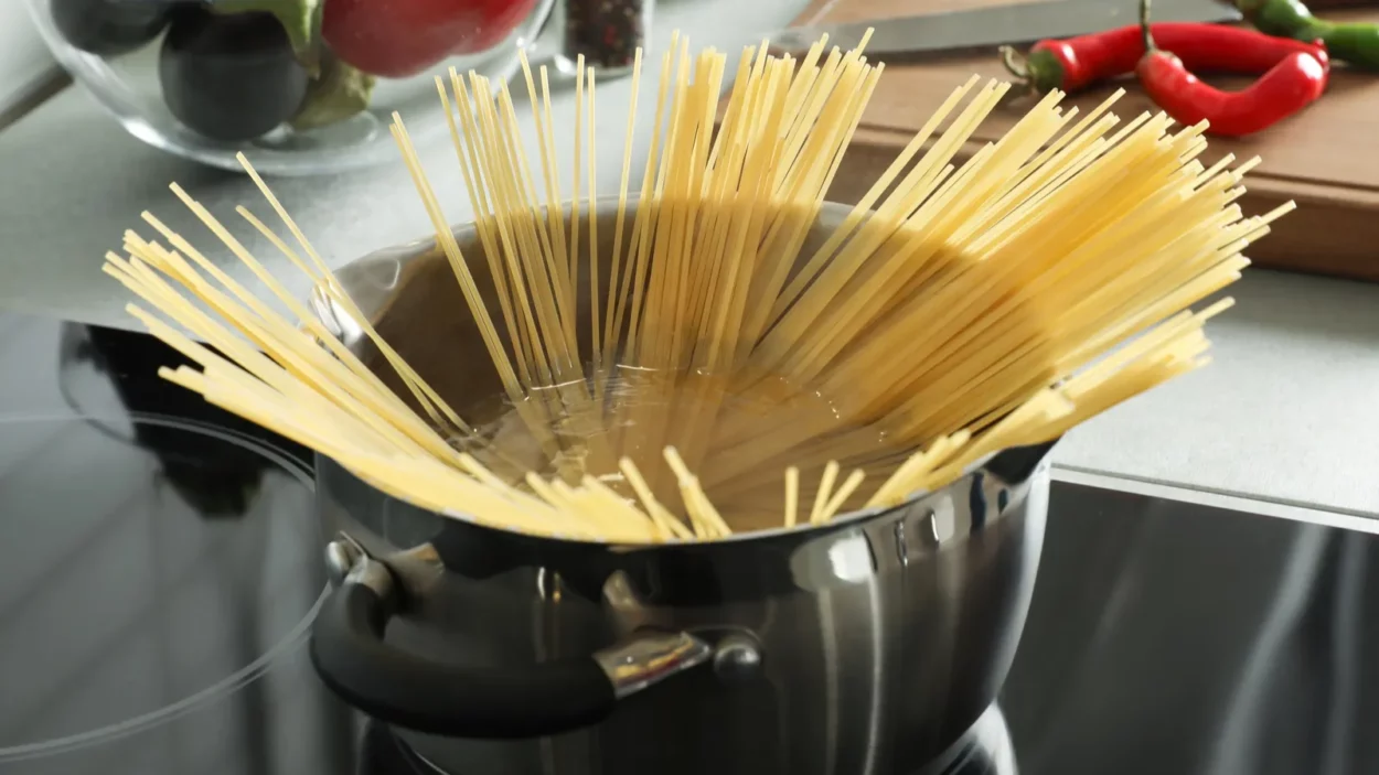 Cooking spaghetti in pot on electric stove.
