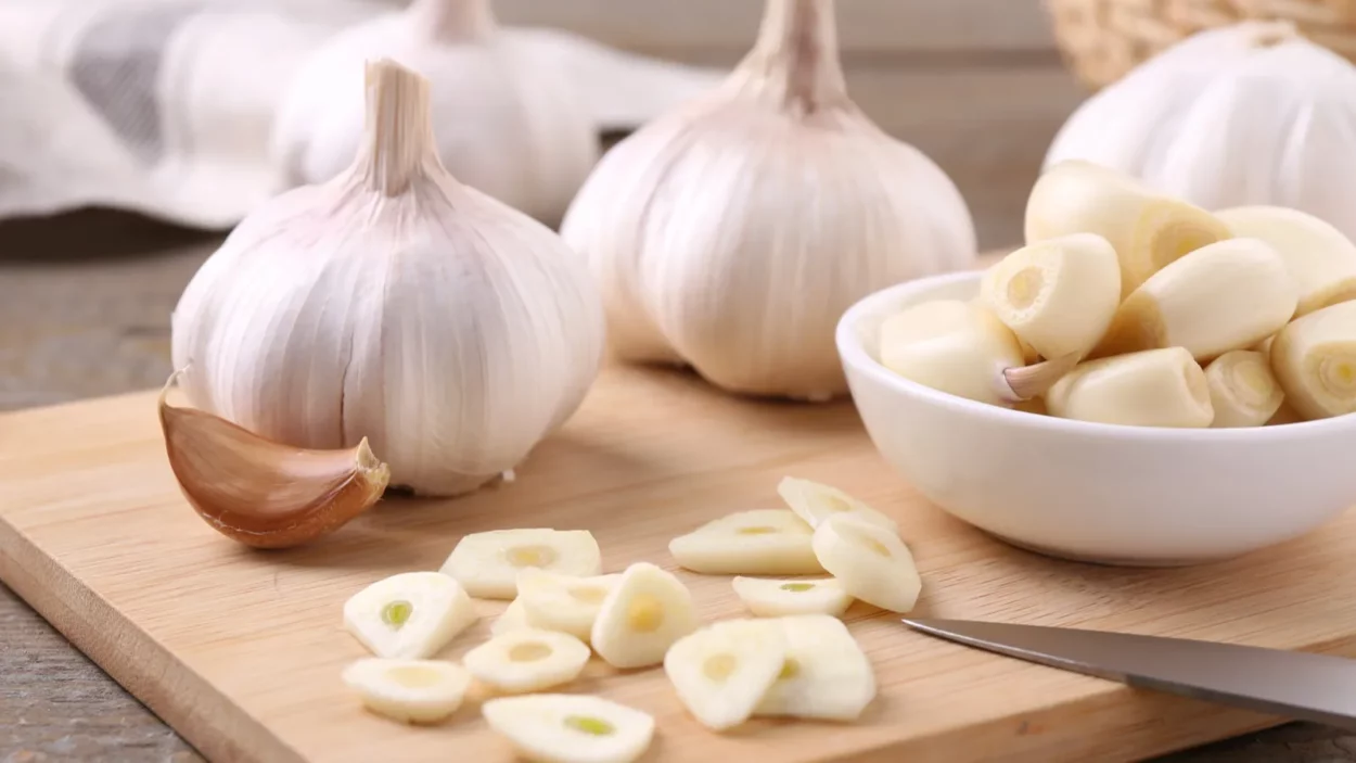 aromatic cut garlic cloves and bulbs on wooden table closeup