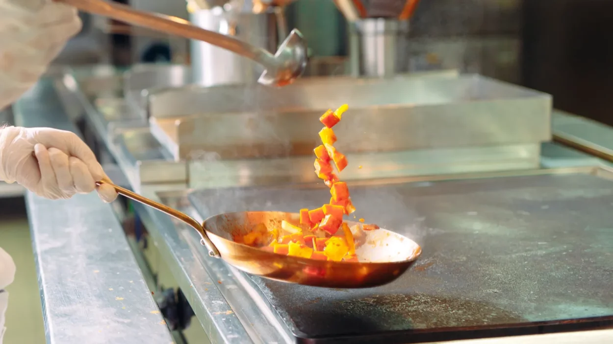 chef cooking vegetables in wok pan shallow dof
