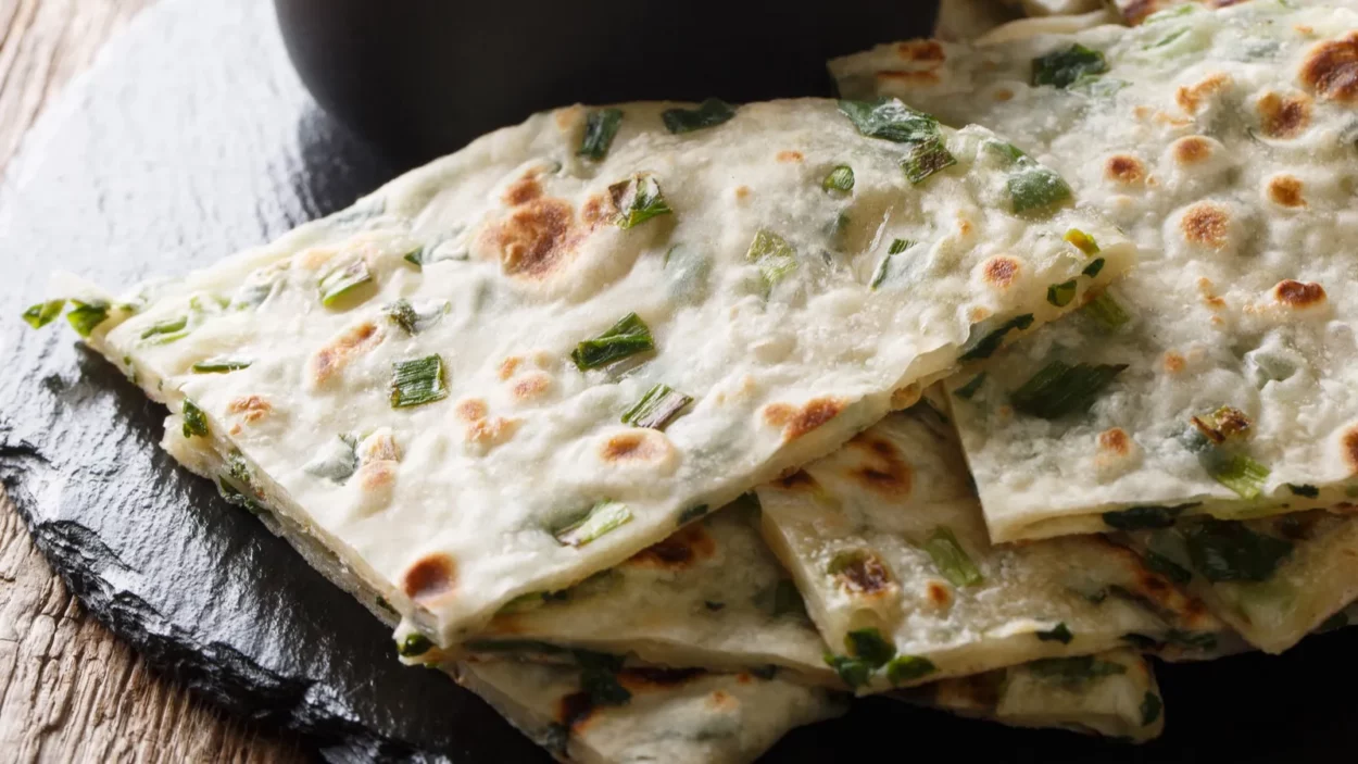 Chinese appetizer fried Scallion pancakes served with sauce close-up on a board on a table.