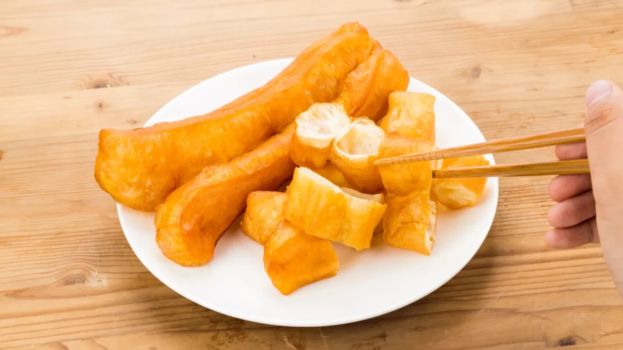 Chopsticks reaching for a piece of You Tiao, or fried bread stick.