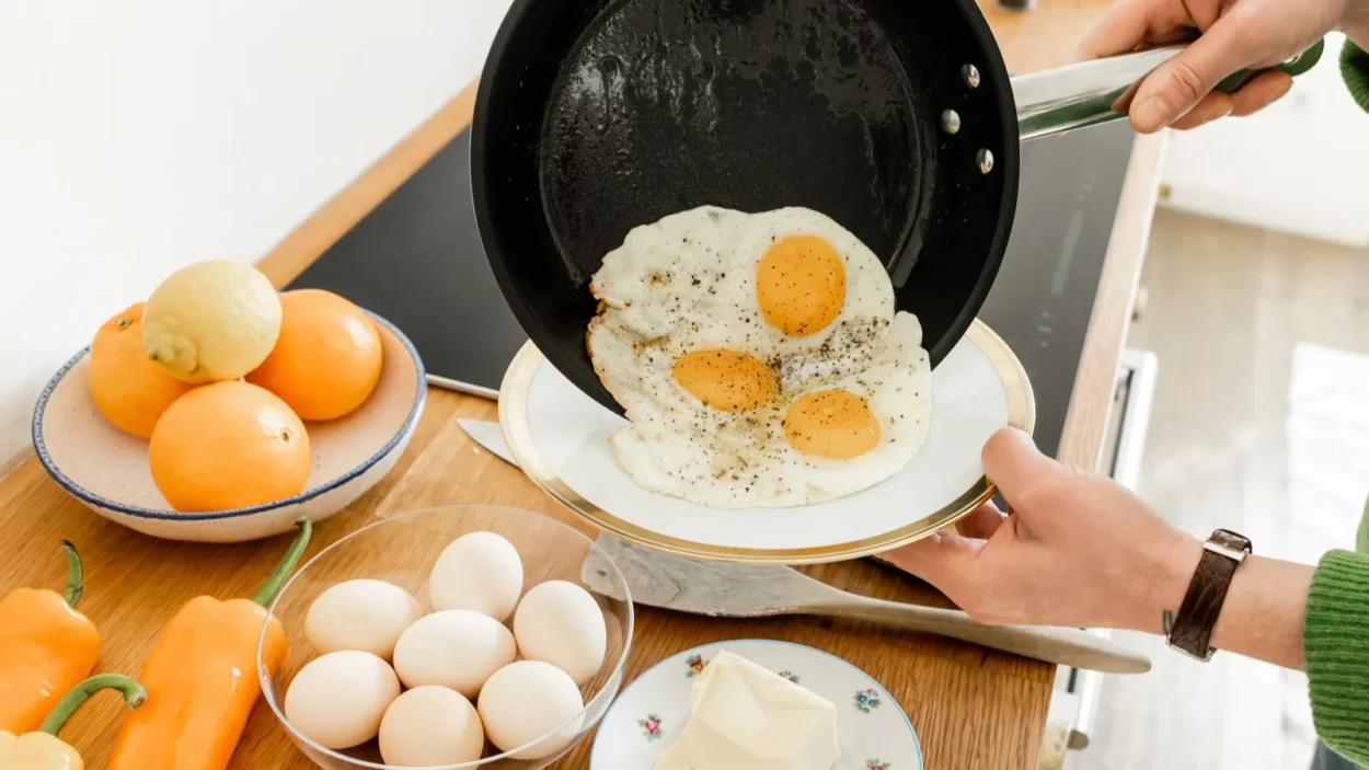Cropped view of man holding pan with fried eggs