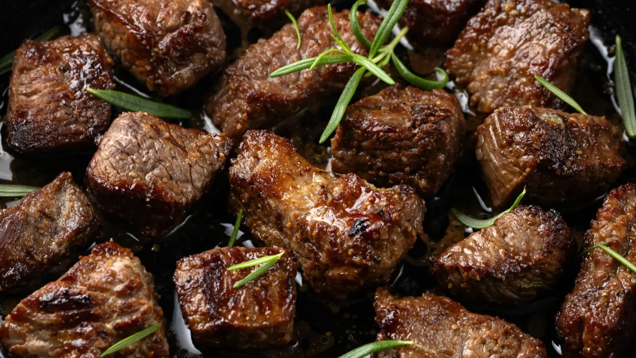 Garlic butter beef steak bites in iron cast pan.