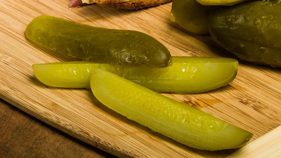 Grilled reuben sandwich with dill pickle spears.