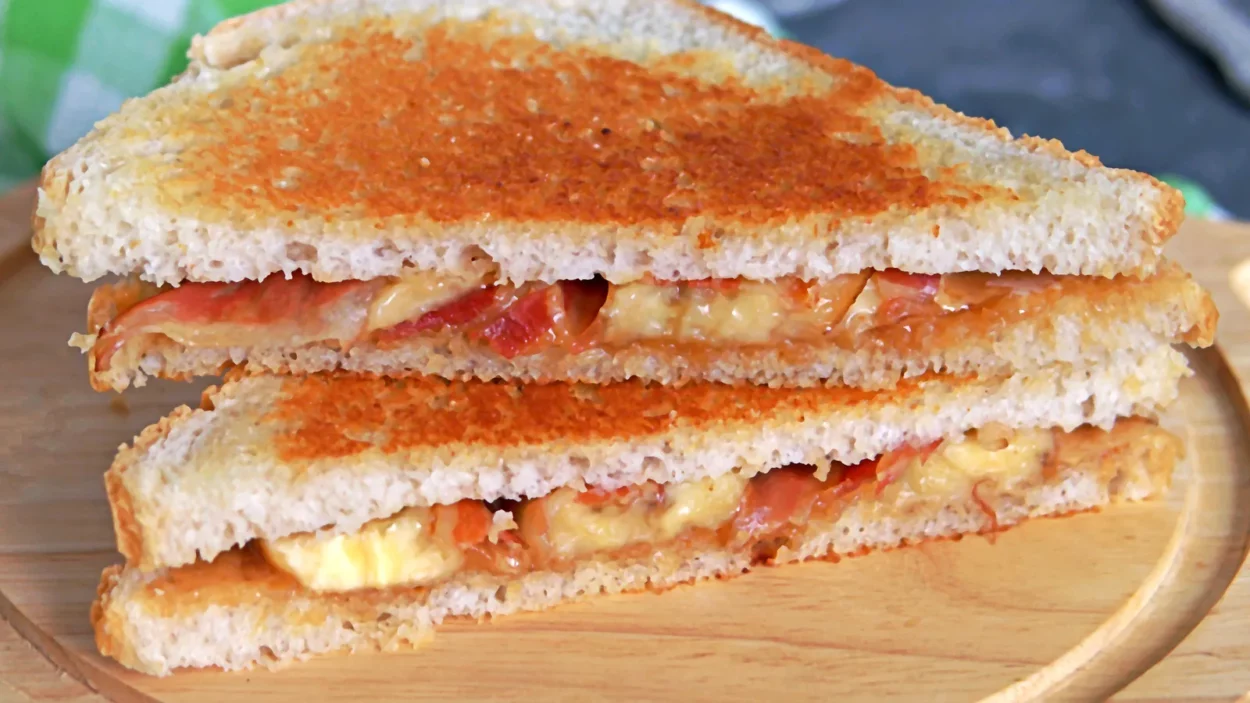 Sandwiches with peanut butter, banana and fried bacon on a wooden board.