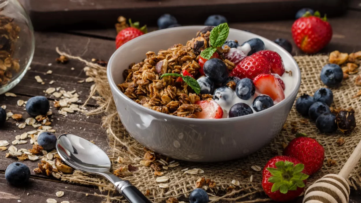 Yogurt with baked granola and berries in small bowl.