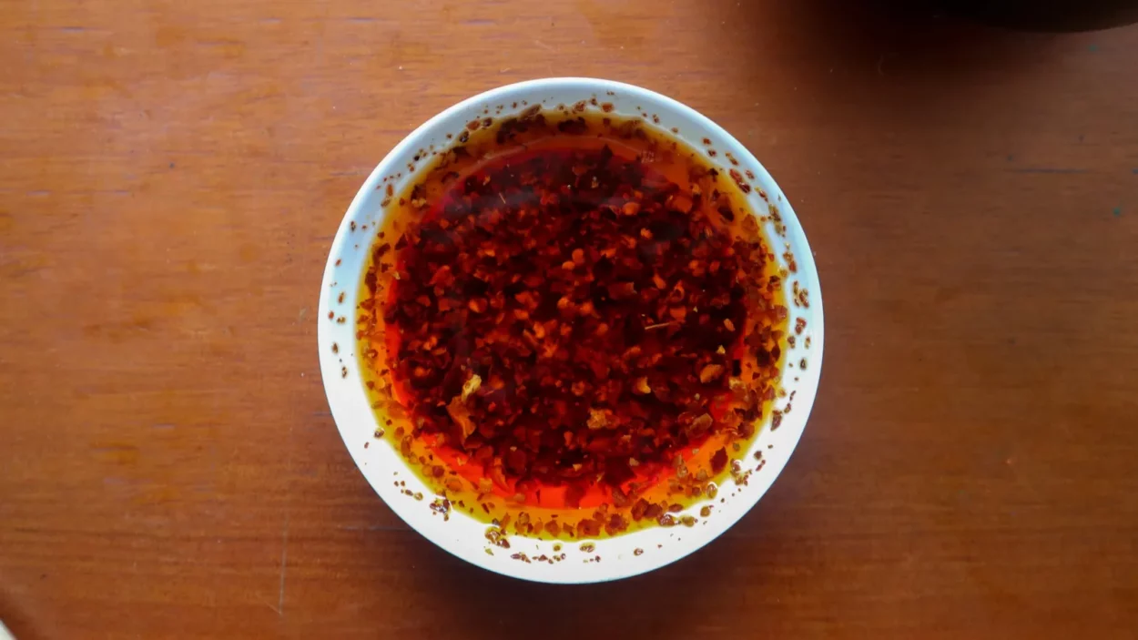 Chilli oil. Homemade chilli oil in a glass like plate, on table.