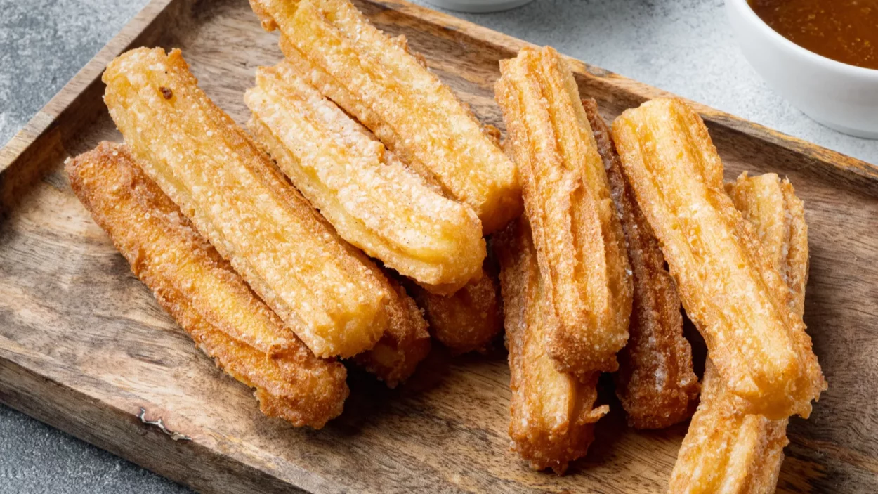 Churros with caramel, Traditional Spanish cuisine, on gray background.