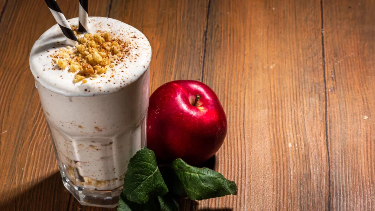 Homemade loaded apple pie milk shake, red autumn apple protein smoothie with tart crumble and spices.