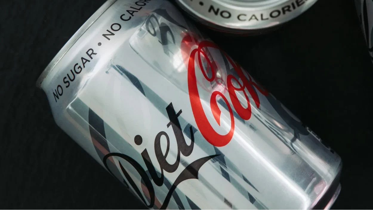 Diet Coke soda cans on dark background.