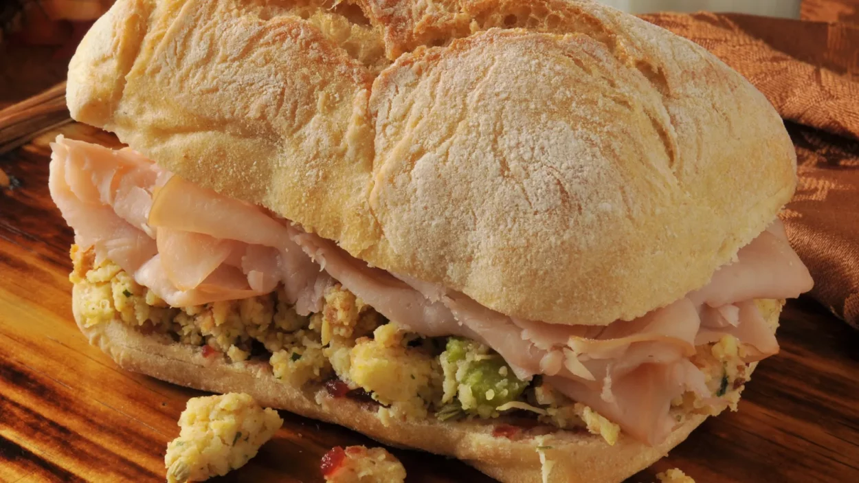 A turkey sandwich with cranberry sauce and cornbread stuffing on a ciabatta roll.