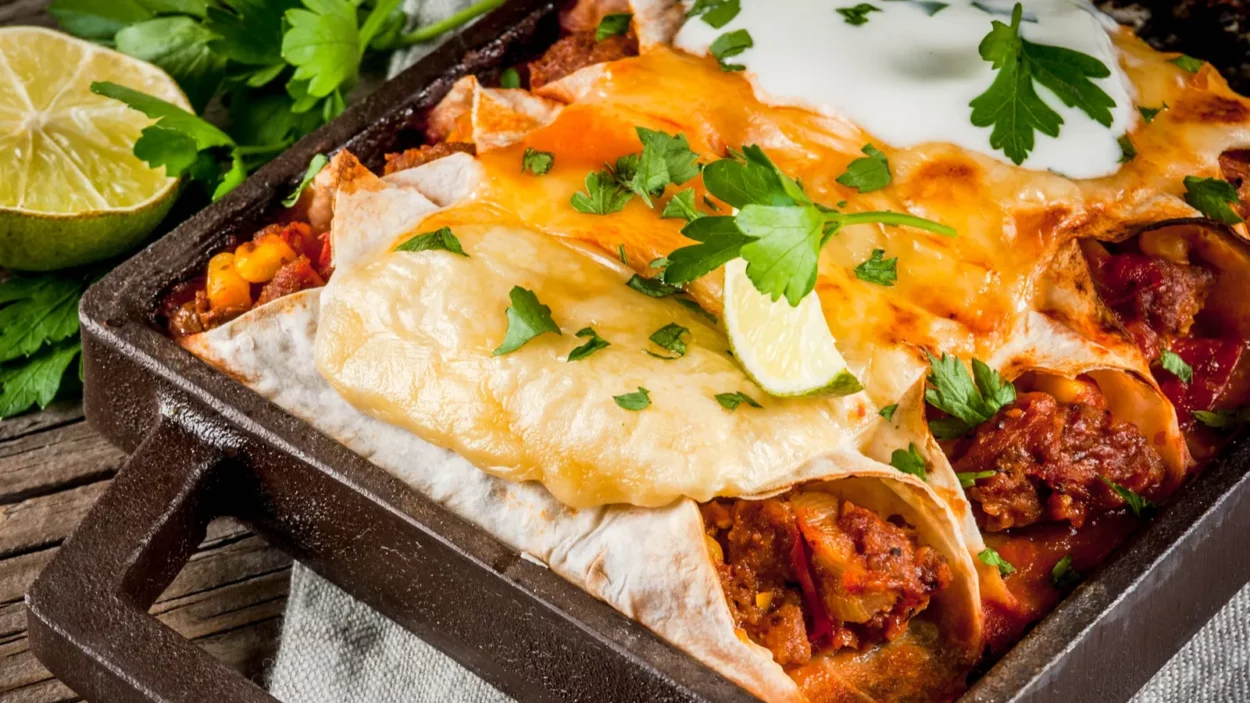 Traditional dish of spicy beef enchiladas with corn, beans, tomato.