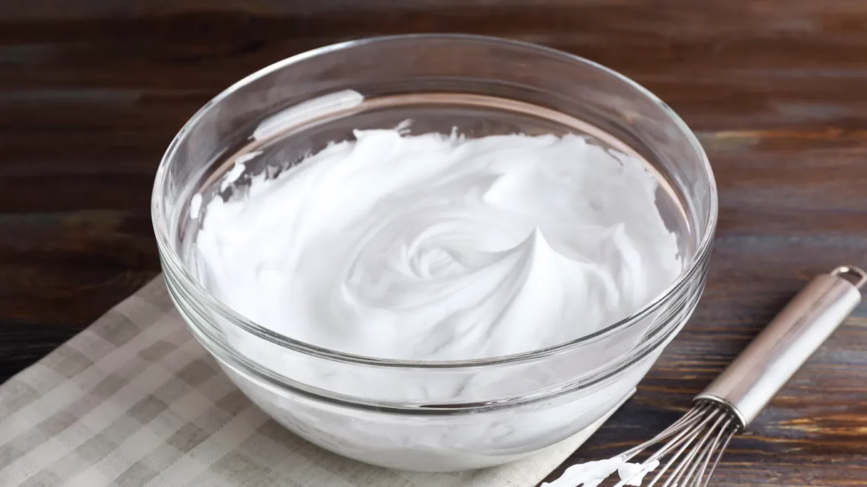 Whipped egg whites for cream on wooden background.