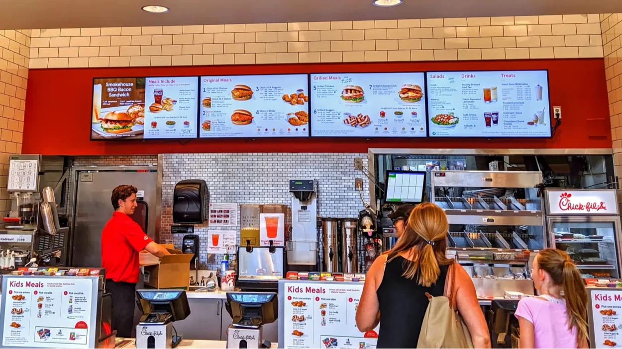 Chick Fil A restaurant menu ordering counter with customers.